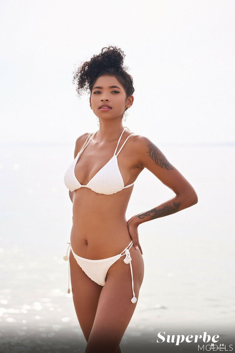 热辣的黑人美女在海滩上调皮地展示着她那有着晒黑线条的迷人乳房和诱人的私处
